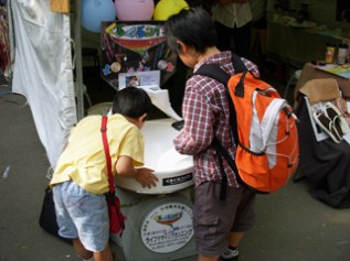 募金箱くるくるコインに夢中な子どもたち