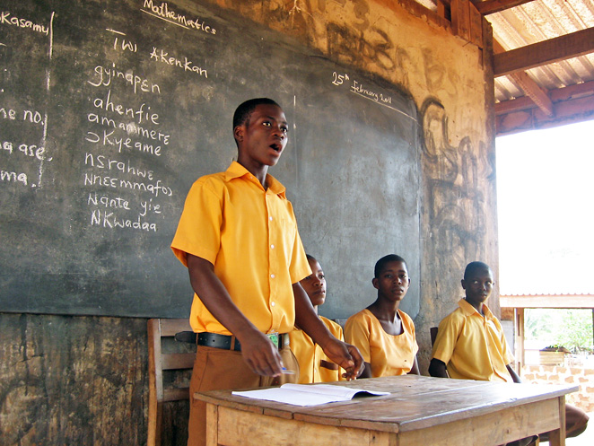 村の学校でみんなの前に立ち発表するゴッドフレッドくん