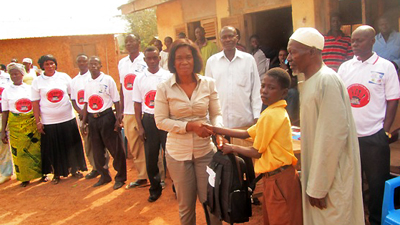 スマイル・ガーナ プロジェクト 学用品を手渡して子どもと握手している郡知事