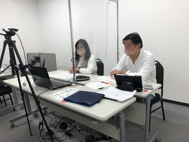 総会の議長を務めた理事小林(右)と議案を説明する代表岩附(左)